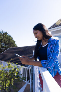 Using smartphone, woman standing on balcony and enjoying outdoor view, copy space