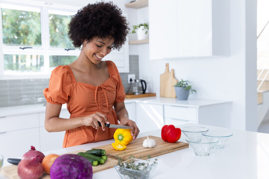 Cutting yellow bell pepper, woman preparing vegetables in modern kitchen, copy space