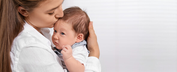 Mother holding her small baby on light background. Banner design with space for text