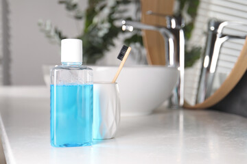 Bottle of mouthwash and toothbrush on white countertop in bathroom
