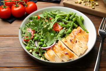 Healthy meal. Tasty salad and chicken breast in bowl on wooden table