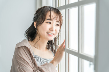 窓際でリラックスする笑顔のアジア人女性
