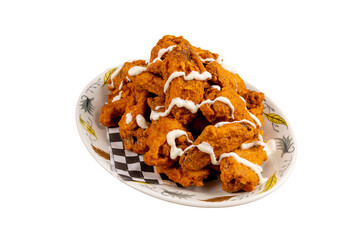 A heaping plate of deep fried chicken wings with a zig zag drizzle of white garlic sauce isolated on white