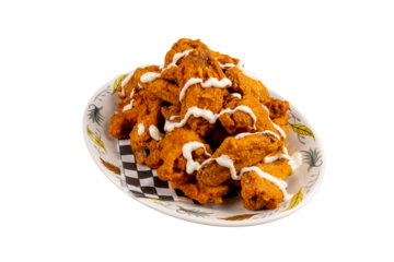 A heaping plate of deep fried chicken wings with a zig zag drizzle of white garlic sauce isolated on white