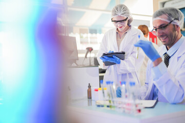 Fototapeta premium scientists perform experiments and record data. people arranges equipment with test tubes and chemicals for producing medicine and biochemistry. man hold tubes of chemical liquids and plant samples.