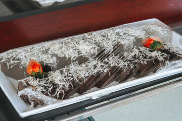 brownies cut into squares on a white plate, wrapping with plastic