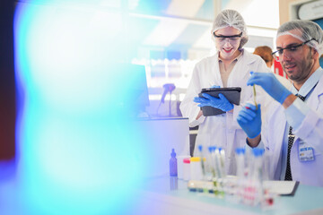 scientists perform experiments and record data. people arranges equipment with test tubes and chemicals for producing medicine and biochemistry. man hold tubes of chemical liquids and plant samples.