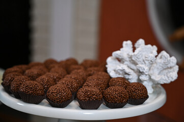close up of chocolate truffles, chocolate candy on a plate, brigadeiro, brazilian sweet, sweet table, birthday party
