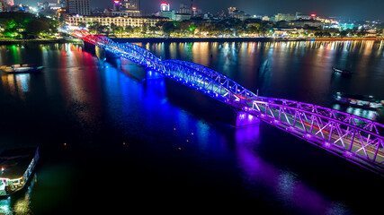 Aerial view of Hue City, Vietnam at night. Bridge illuminated all over with blurry reflection on water