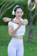 Fototapeta premium Beautiful Asian female runner doing morning exercise outdoors in Asian sports park. Beauty. Slim body warming up in sports clothes. Relax and get a fitness workout by stretching your muscles.