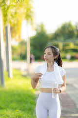 Beautiful Asian female runner doing morning exercise outdoors in Asian sports park. Beauty. Slim body warming up in sports clothes. Relax and get a fitness workout by stretching your muscles.