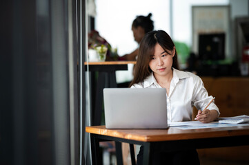 Young Hispanic Asian student using laptop in university campus or at virtual office. College female...