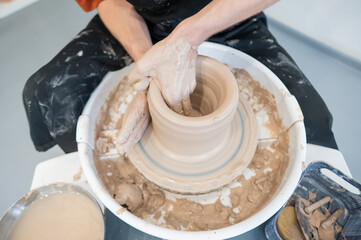 Close-up of a potter's hands working on a pottery wheel. 