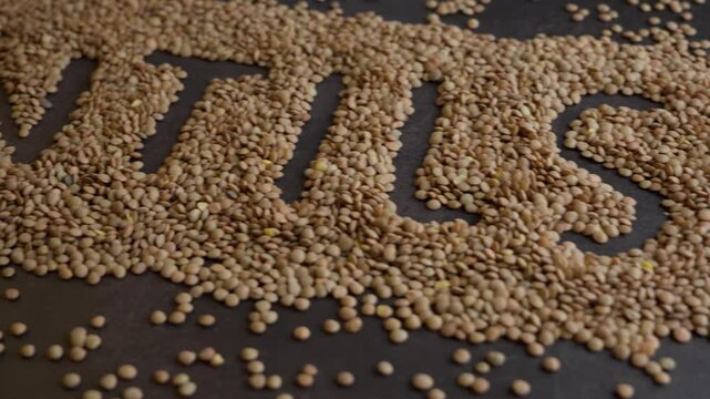 The word lentils with brown lentils on black background, Travel shot rigth