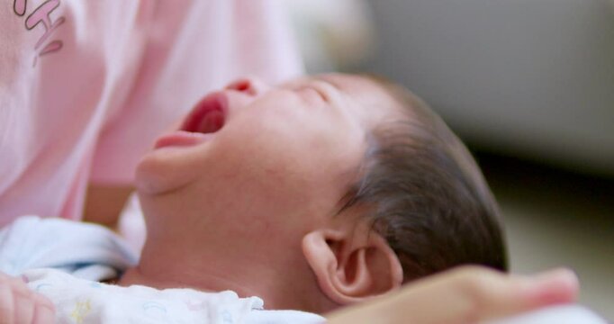 Baby keeps crying as its mother is trying to give some milk inside a baby bottle to calm the baby down and relieve it from colic.