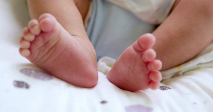 A baby's tiny feet are kicking and stretching as it is lying on its crib inside the nursery.