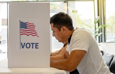 Hispanic Person Voting in Election Booth. a young man focused on voting in an election booth during...