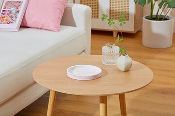 Close up shot at a wooden table in living room, on top displaying an empty podium in round shape for showing product. Lifestyle photo from high angle with space for designing