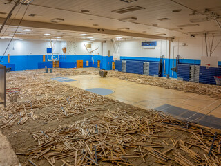 Removal of an old wooden plank gymnasium floor as part of a gym renovation project.