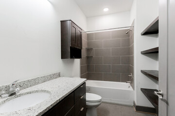 Contemporary Bathroom With Granite Countertop And Tiled Bathtub Area