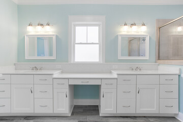 Calm Bathroom With Dual Sinks, White Cabinets, Large Mirrors, And Teal Accent Wall