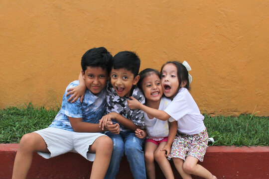 Two happy and excited dark-skinned Latino boys and 2 girls celebrate Children's Day by playing and laughing