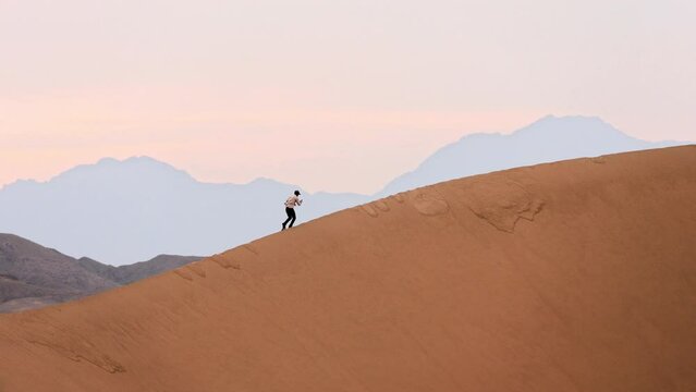 Man walking, climbing the barchan in the desert, Singing barchans, Kazakhstan, Altyn Emel, desert, steppe, sand | Человек идёт, поднимается на бархан в пустыне, Поющие барханы, Казахстан, Алтын Эмель,