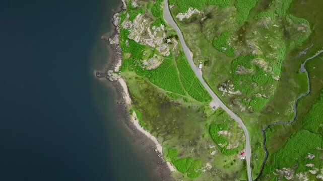Rugged lake shore with polarised view of bank drop-off into dark lake depths. Lakeside road and greenery. Top down high altitude drone view. Wastwater, Wasdale, Lake District, Cumbria, England, UK