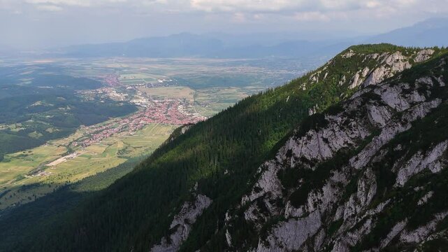 Drone pulls back, revealing Zarnesti city and Piatra Mica peak