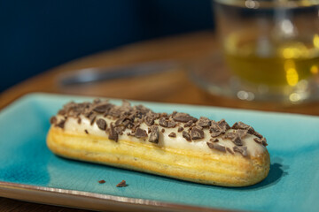 A chocolate covered pastry sits on a blue plate
