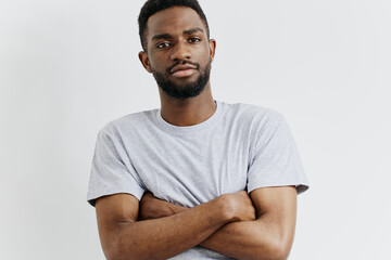 Confident young black man in casual grey tshirt standing against a clean white background