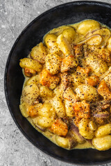 turmeric gnocchi with pumpkin and onion in creamy sauce, healthy plant-based food