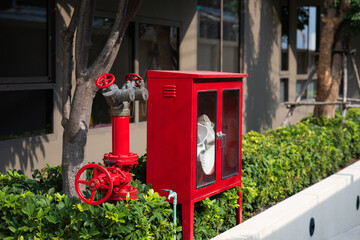 Red fire hose cabinet with full equipments, pip line and red round water supply valve near the...