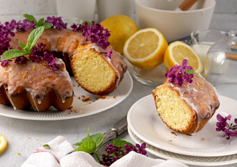 Still life of lemon cake with slice and with lilac on white table