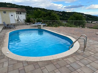 Transparent blue water in the pool and stainless steel railings. Swimming pool with handrails for entry, close-up.
