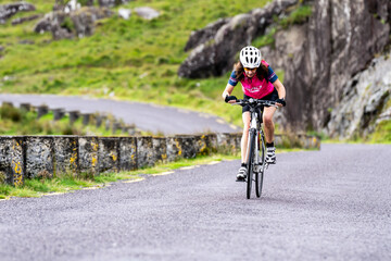 female cyclist ascending Healy Pass (R574) on the Beara peninsula, Ireland, United Kingdom