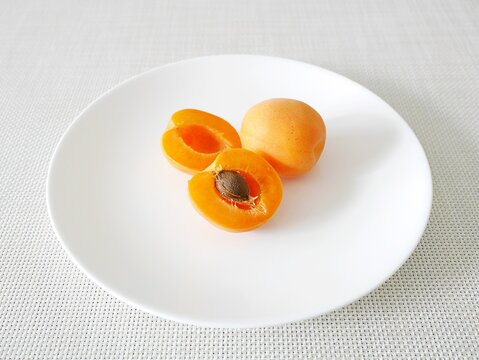 白い皿の上の生食用あんず「おひさまコット（サニーコット）」（断面・種あり）