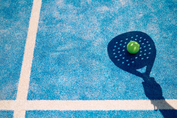 Shadow of paddle tennis player hitting  ball on court. © Drazen