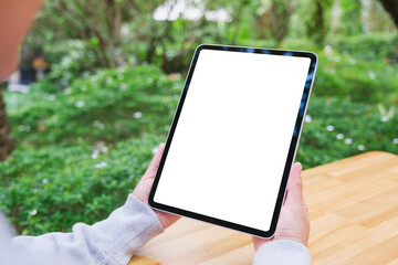 Mockup image of a woman holding digital tablet with blank white desktop screen in the outdoors