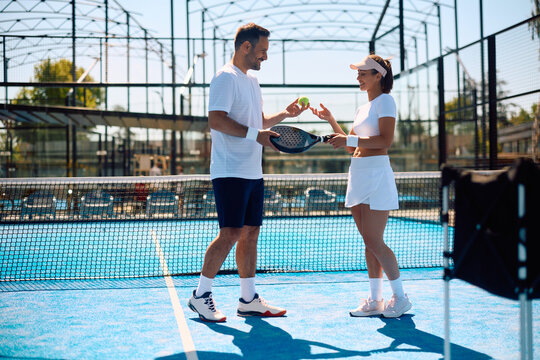 Happy athletic couple on paddle tennis court.