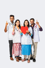 Heart Care concept - Indian group of young doctors holding red heart shape cardboard cutout against white background