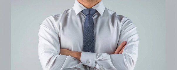 A man wearing a white shirt and a blue tie is standing with his arms crossed. Concept of professionalism and confidence