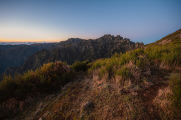 Naklejka premium Hiking on the highest peak of Madeira Pico Ruivo next to the cottage Abrigo do Pico Ruivo. Views of the surrounding mountains lanscape during sunrise