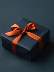 A blue gift box with orange ribbon and bow, placed on a dark background, creates an elegant and luxurious atmosphere. Present for a holiday, birthday or Christmas.