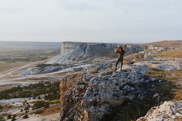 Man standing on cliff edge with arms raised in travel adventure moment of triumph and freedom