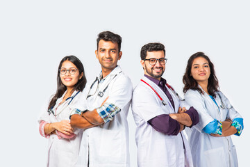 Group portrait of four indian asian young doctors in uniform standing against white background