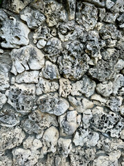 Piece of masonry wall made of uneven gray stones, vertical abstract background