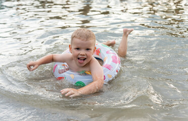 Boy 3 years old swimming in inflatable swimming ring on lake. Safety of the baby in the water. High quality photo