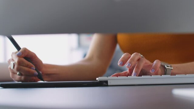 Close up of hands of female architect working on desktop computer in office using graphics tablet- shot in slow motion