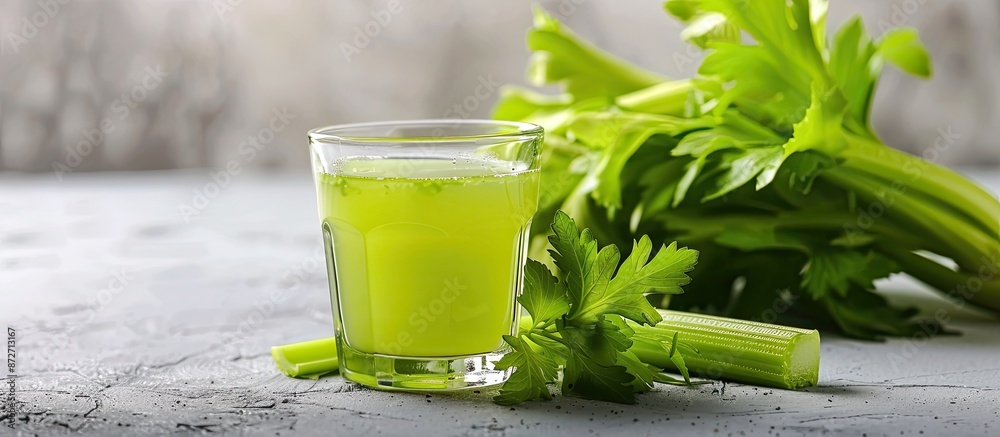 Fototapete on a white table, there is a glass of celery juice and fresh vegetables, with room for adding text i
